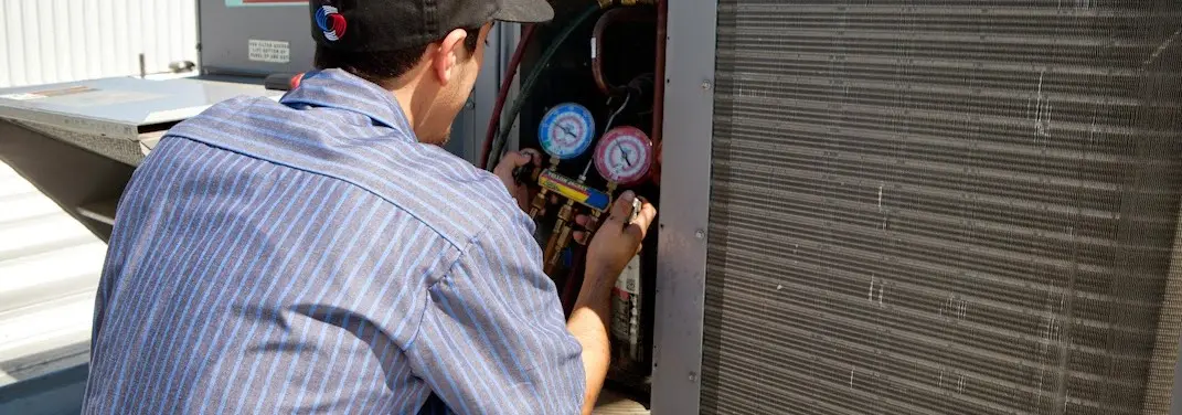 HVAC technician servicing a condenser unit in Montclair
